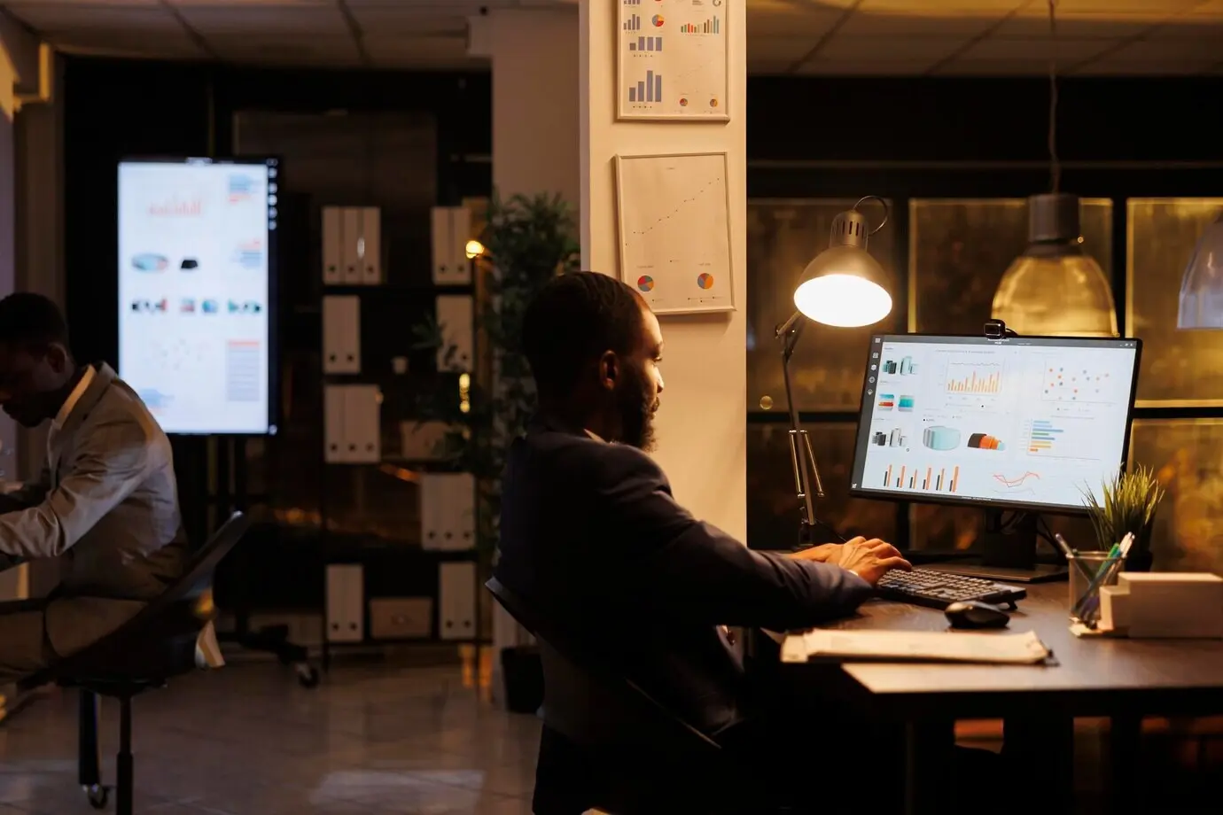 African American manager analyzing marketing statistics while working overtime on the project strategy in a startup office. Entrepreneur planning a business investment to help increase the company’s profit.
